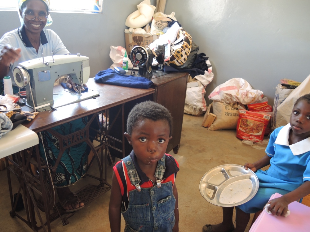 A boy at the Franciscan Sisters’ feeding program, in front of a woman who received training for sewing. (Melanie Lidman)