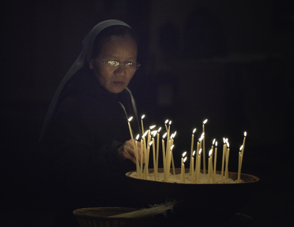 Sr. Hien Nguyen of Vietnam lights candles at a July 22 interfaith service at St. Paul's Anglican Cathedral in Melbourne, Australia. The event was a memorial service for those who have died of HIV- and AIDS-related causes and included the involvement of several delegates to the 20th International AIDS Conference. (CNS photo/Paul Jeffrey)