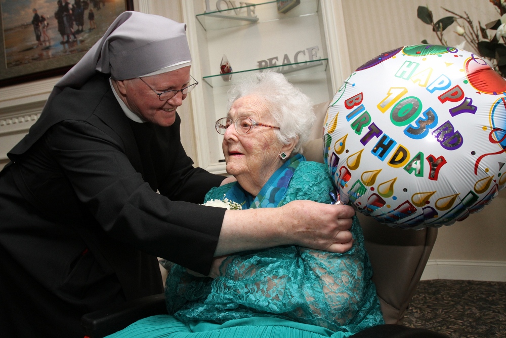 Sr. Elisabeth Anne Roche adjusts a balloon next to honoree Rita Driess, who will turn 103 March 9, during a birthday party for centenarians Jan. 20 at the Little Sisters of the Poor's Queen of Peace Residence in the Queens borough of New York. Driess is one of eight residents celebrating 100 or more years in 2015. (CNS photo/Gregory A. Shemitz)