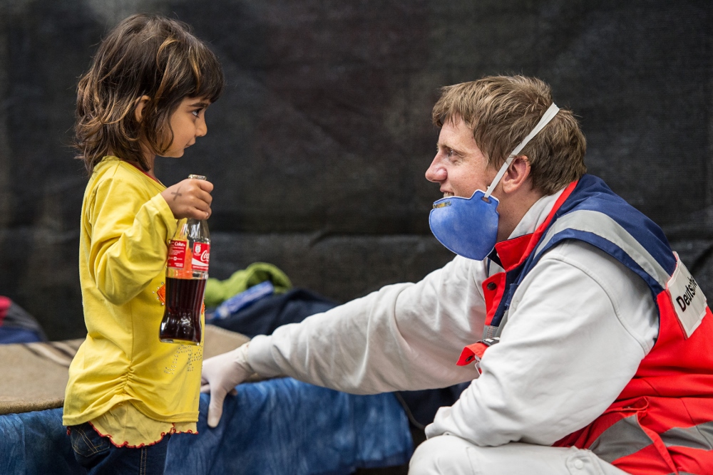 A volunteer from the German Red Cross plays with a migrant girl from Syria in an emergency shelter in Rottenburg Sept. 16. (CNS photo / Wolfram Kastli, EPA)