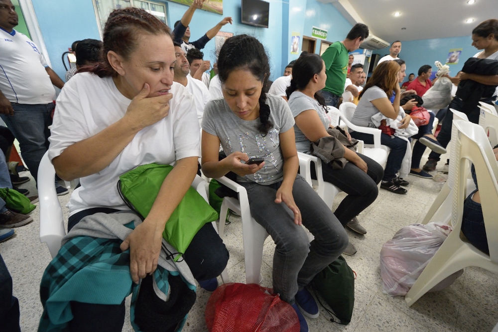 Honduran women deported from the United States use their phones to contact family and friends after they arrived at a church-run center in the San Pedro Sula airport Dec. 17. They were flown to the airport aboard a U.S. government flight, then bused to a remote section of the airport where the Catholic church operates a Center for Attention to Returned Migrants. (CNS photo/Paul Jeffrey)