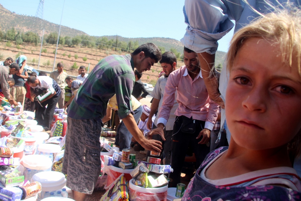 Members of the Yezidi religious minority who fled from violence in Mosul, Iraq, receive humanitarian aid Aug. 21 in Dohuk province, in the northern part of the country. Catholic relief agencies are trying raise more money for additional aid in the region. (CNS photo/EPA)