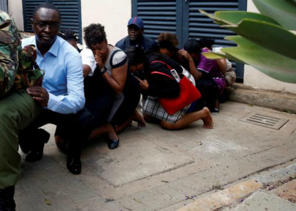 People are evacuated by a member of security forces Jan. 15 at the Dusit hotel compound in Nairobi, Kenya. An Islamic militant group stormed the luxury hotel in Kenya's capital, setting off explosions and gunning down people at cafe tables in an attack that killed at least 15 people. (CNS/Reuters//Baz Ratner)