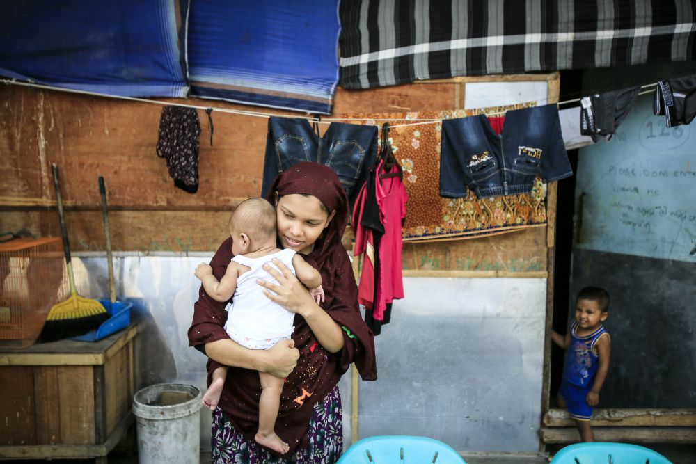 A Rohingya woman holds her 2-month-old baby in early February at a refugee shelter in Medan, Indonesia. The woman and her husband fled persecution in their village in Myanmar and have been waiting for two years to be resettled to Malaysia or Australia. (CNS photo / Dedi Sinuhaji, EPA)