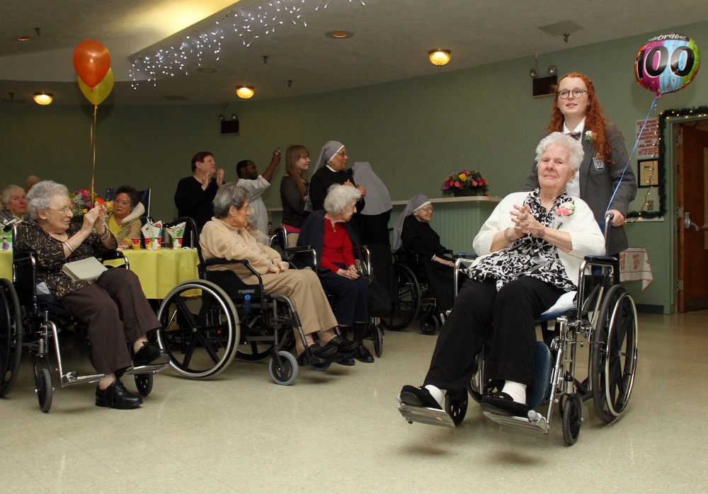 Honoree Agnes Russo, who will turn 100 Sept. 9, is escorted by junior Fiona Danyko of Kellenberg Memorial High School in Uniondale, N.Y., during a birthday party for centenarians. (CNS photo/Gregory A. Shemitz)
