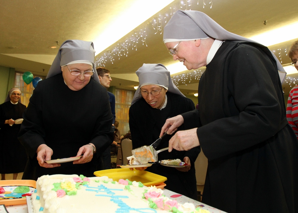 Srs. Carol Ferrucci, left, Maria Goretti Hung and Margaret Regina Halloran prepare to distribute cake during a birthday party for centenarians Jan. 20 at the Little Sisters of the Poor's Queen of Peace Residence. (CNS photo/Gregory A. Shemitz)
