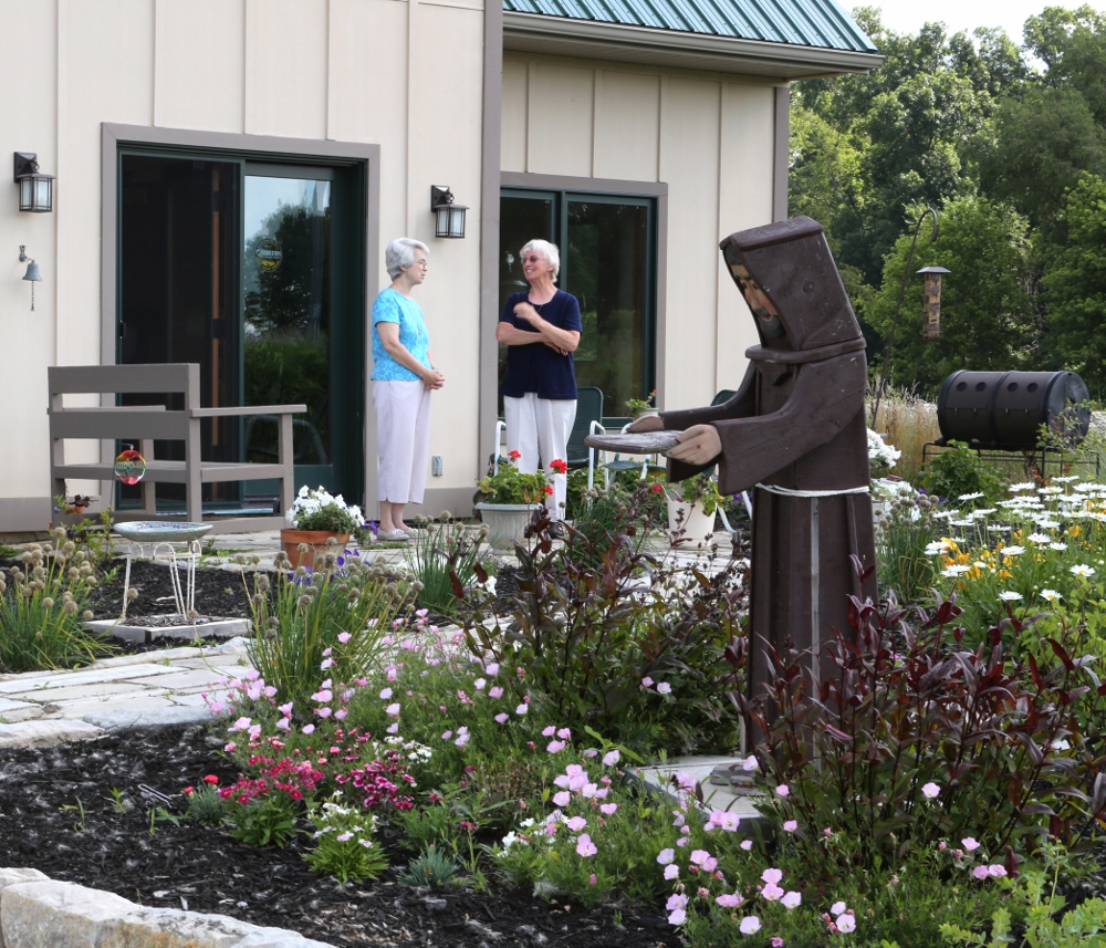 St. Francis Sr. Jane Frances Omler (right) and St. Francis Sr. Jacqueline Doepker talk on the patio of the energy-efficient straw-bale house they helped build in Tiffin, Ohio. (CNS photo/Chaz Muth)
