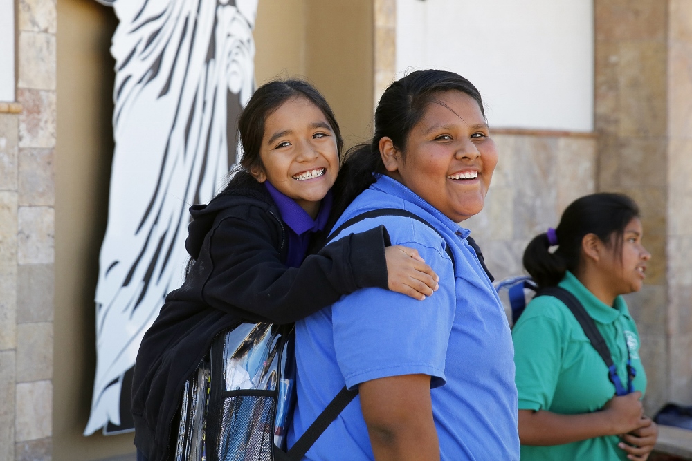 Lorenzo Casas, left, and Lydia Antone wait for a bus at the end of the school day at St. Peter Indian Mission. (CNS photo / Nancy Wiechec)