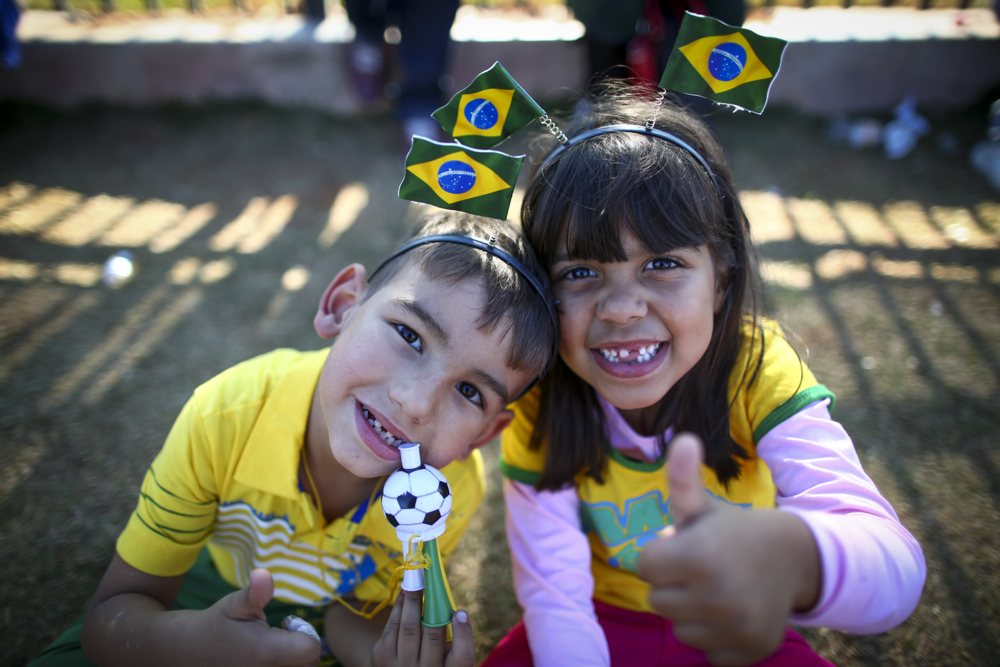 Young Brazilian fans pose for a photo outside the Arena Corinthians stadium in Sao Paulo June 11, the day before the FIFA World Cup finals began. At the Vatican, Pope Francis told fans, players and organizers the World Cup should be a celebration of solidarity and peace, including his thoughts that the idea of fair play helps people “overcome individualism, egoism, all forms of racism, intolerance and exploitation.” (CNS photo/Diego Azubel, EPA)
