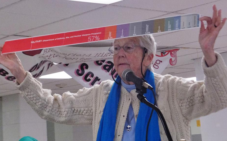 Sr. Megan Rice holds up a measuring scroll produced by the American Friends Service Committee showing that United States spends 57 percent of its revenue on militarism, more than other nuclear-armed nations. (GSR photo / Patricia Lefevere)
