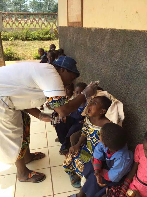 Sister Colette, matron of the Catholic Health Center in Massea, gives multivitamin syrup to the children at Alfred Therese Nursery and Primary School. (Provided by Constance Fonju)