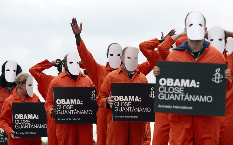 Masked activists from Amnesty International dressed as Guantanamo Bay detainees protest the military-run prison June 16 outside Waterfront Hall in Belfast, Northern Ireland, prior to the Group of Eight summit, which President Barack Obama attended. (CNS/Reuters/Cathal McNaughton)