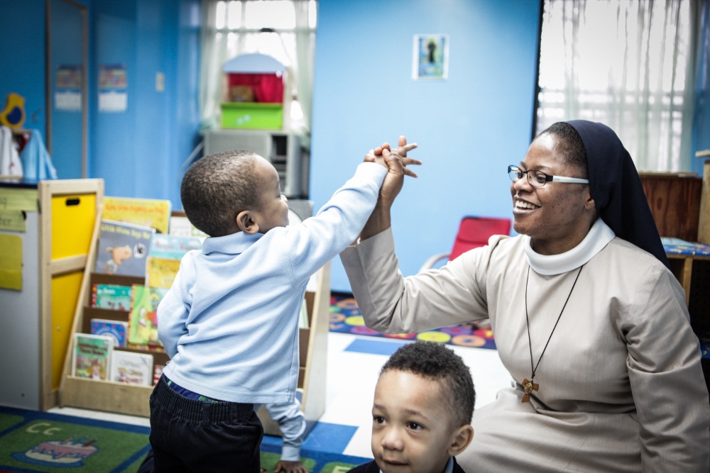 A child at St. Benedict's Day Nursery gives Sr. Mary Adenubi a high five. (Regina Fleming, courtesy of Franciscan Handmaids of the Most Pure Heart of Mary)