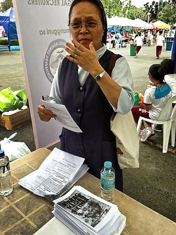 A nun reads through an anti-trafficking leaftlet handed out to Typhoon Haiyan survivors at the Philippine Air Force Base in Pasay City, Philippines, beginning Nov. 16. (Courtesy of Inter-agency Council Against Trafficking)