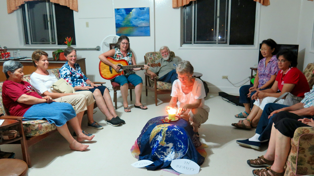 Web of Life participants watch Maryknoll Sr. Peg Dillon light a candle on the altar during the opening night of the Web of Life retreat. (Tracy Barnett)