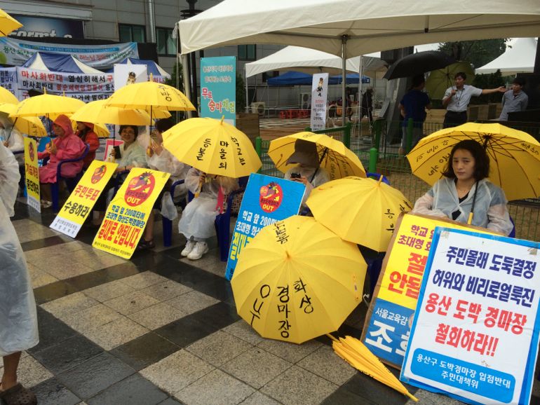 Sacred Heart sisters, school teachers, parents and students maintain daily protests adjacent to the Korean Racing Authority building. Rain does not stop their vigil, day or night. (Tom Fox)