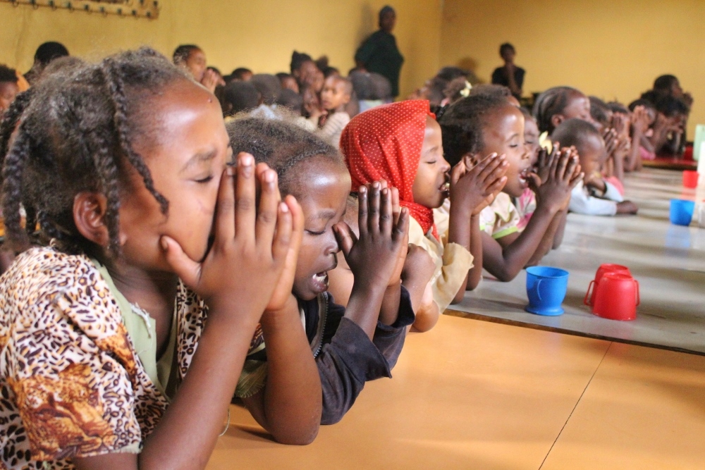 The children pray before a meal. (Christian E. Ruehling)