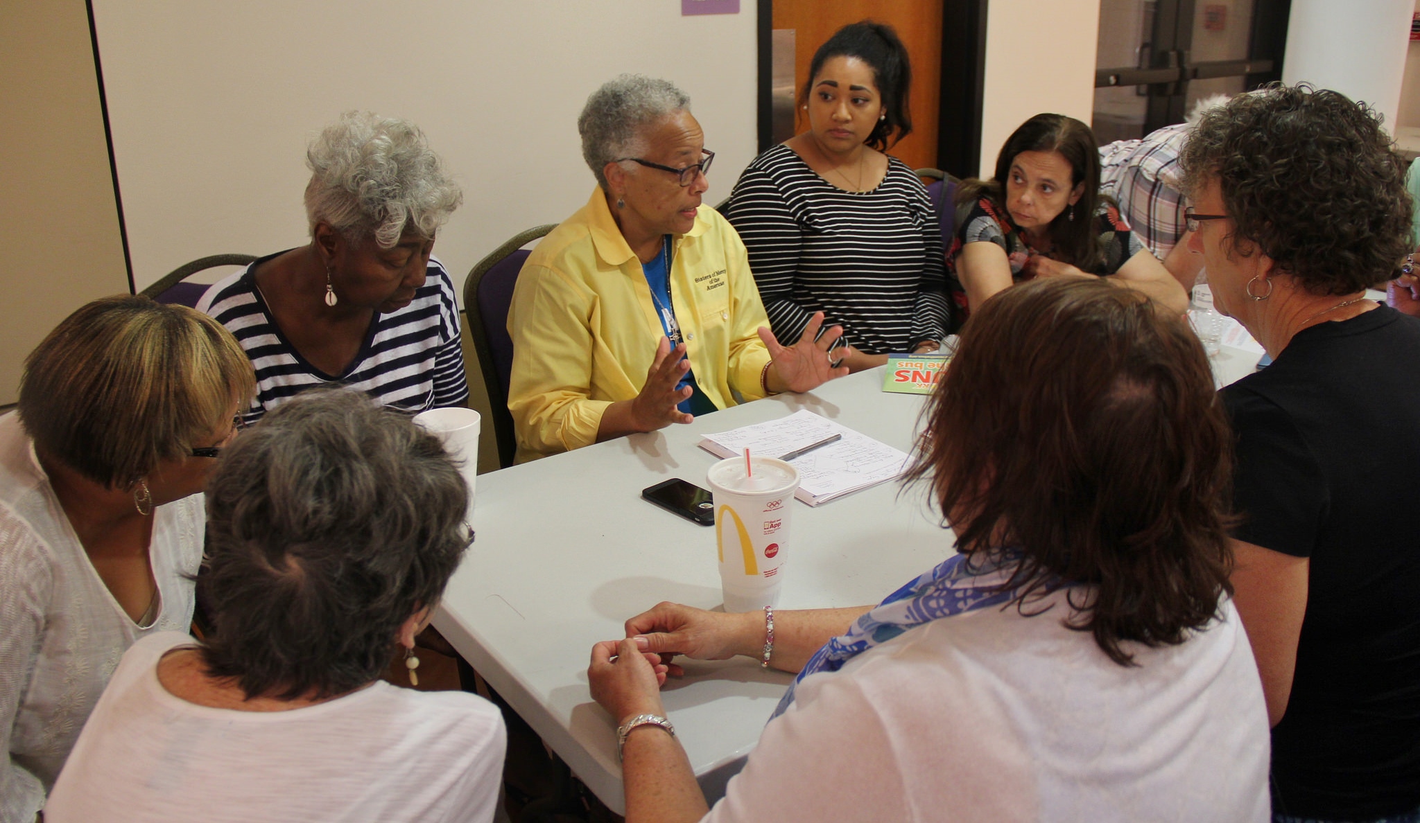 Sr. Larretta Rivera-Williams, in yellow, talks to community members of Jefferson City, Mo., at an evening caucus July 13. (Jennifer Wong / Courtesy of NETWORK)
