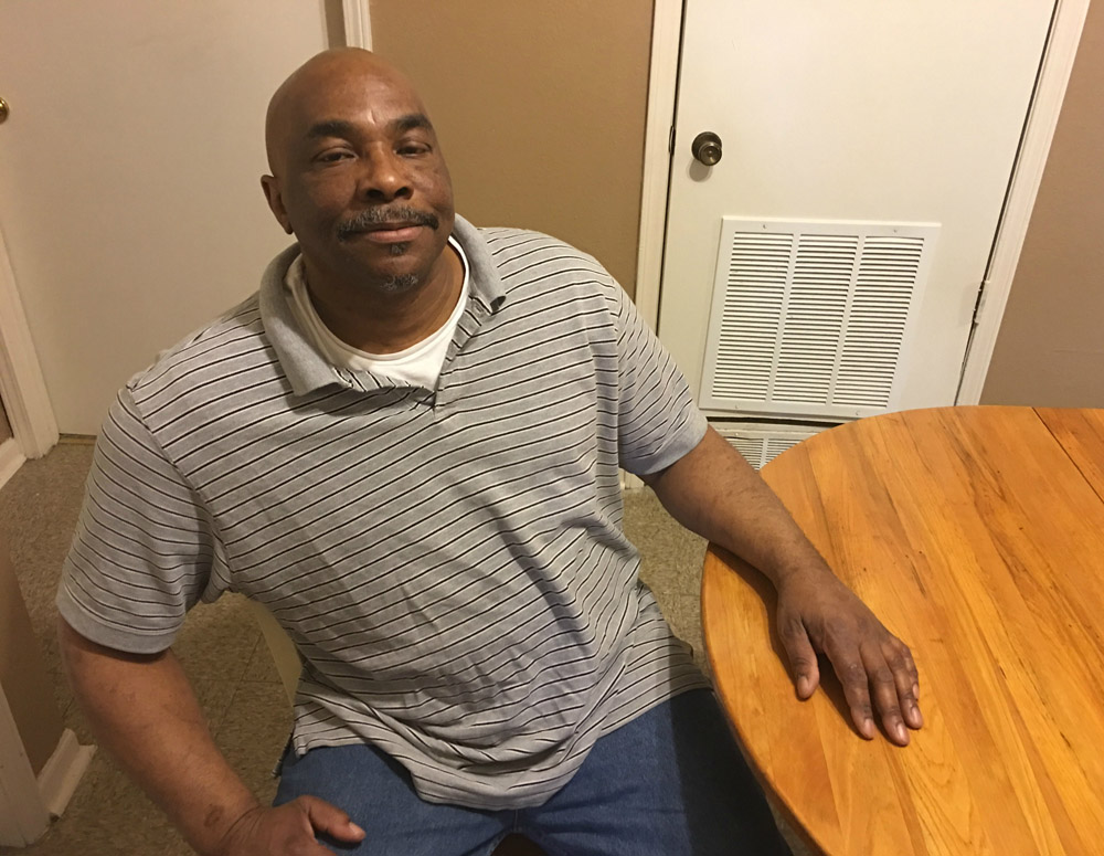 Loren May sits in his apartment on the northeast side of Kansas City, Missouri. It's the second apartment he's had since leaving prison in 2014. He and his fiancée, Ira, maintain a 'prayer wall' in their dining room — a photo collage of all their many blessings. (GSR photo / Dawn Araujo-Hawkins)