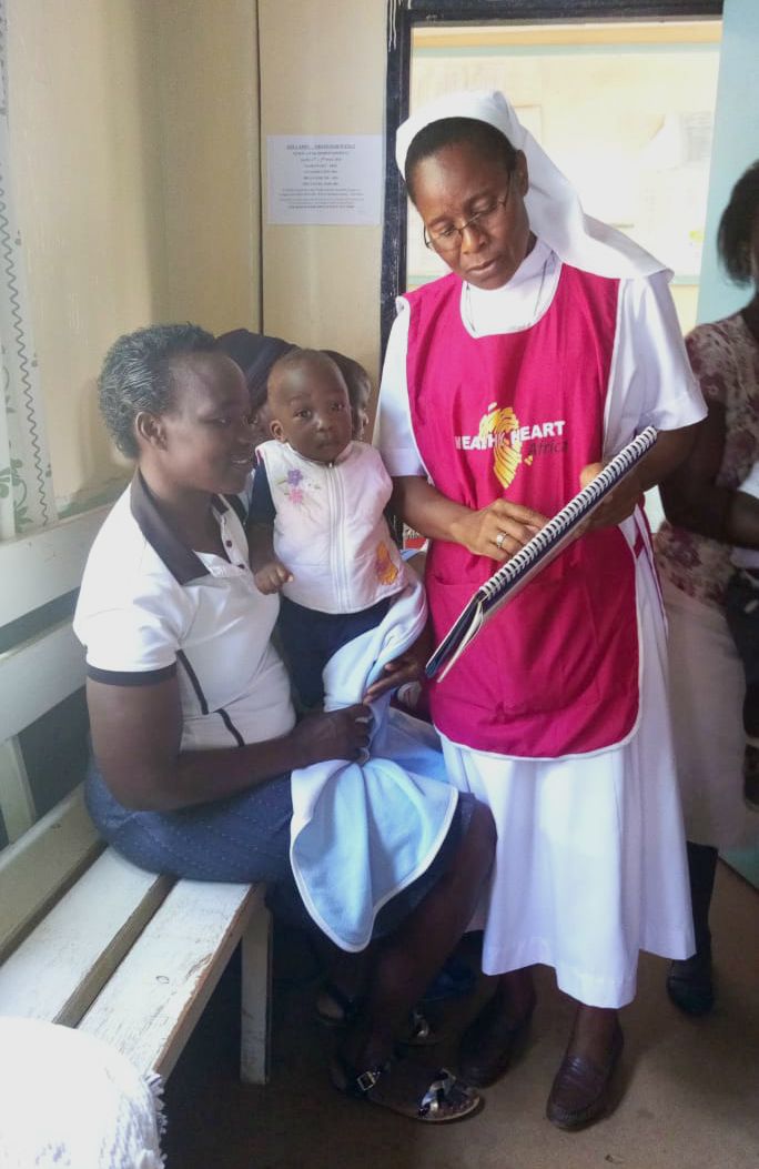 Sr. Mary Nafula shows a mother a nutrition chart while getting feedback on how her child is responding to medication. (Provided photo)