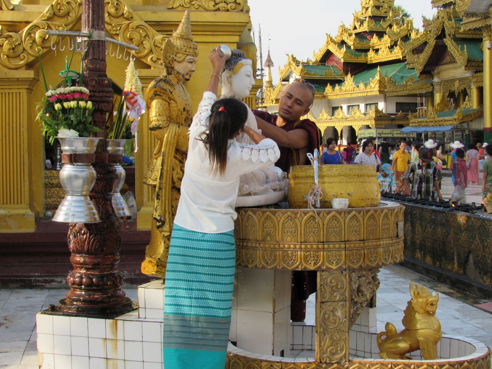 A family makes offerings of flowers and water at one of the many images of Buddha in Yangon's Shwedagon Pagoda, Myanmar's most revered shrine. The pagoda is said to hold eight hairs of Buddha. (CNS photo / Barb Fraze)