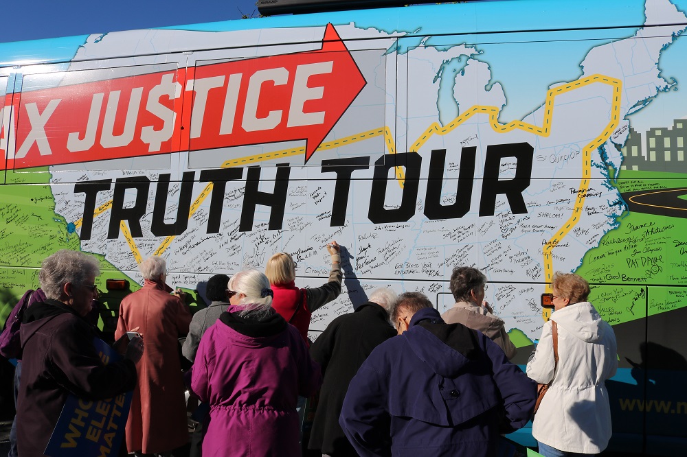 Attendees of the Oct. 16 Nuns on the Bus rally outside the office of U.S. Rep. Don Bacon sign the bus in Omaha, Nebraska. (Network Lobby for Catholic Social Justice / Colleen Ross)