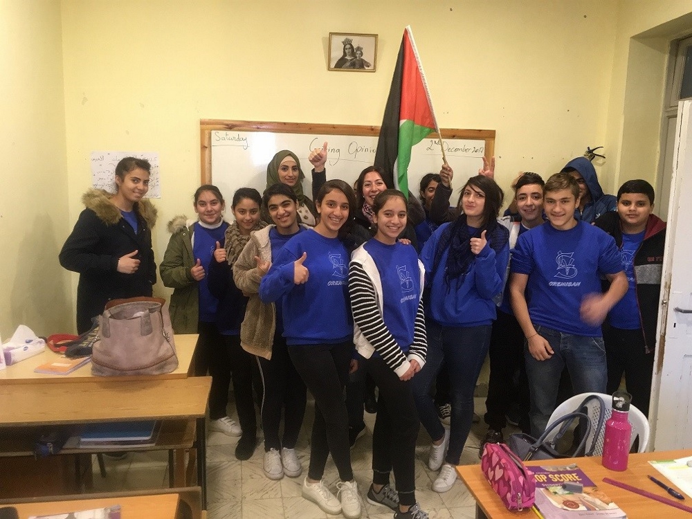 Natalia Liviero is pictured with ninth-grade students. There is a picture of Mary Help of Christians and the Palestinian flag in every classroom. (Provided photo)