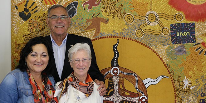 Sr. Kay McPadden, a Josephite sister, right, with Ravina Waldren and David Miller, is passionate about her ministry among Aborigines. Behind them is an example of aboriginal art. (Courtesy of The Catholic Leader)