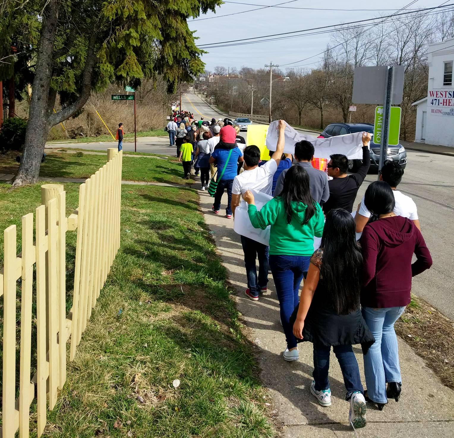 Immigrants and allies walk through Sr. Tracy Kemme's neighborhood during an immigration rally in 2015, a symbolic act of sharing the journey. (Jeremy Bauer)