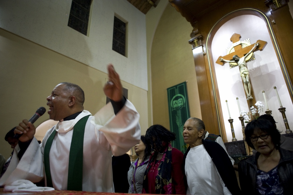 Fr. Chester Smith, a member of the Society of the Divine Word, invites worshippers to join him on the altar on the second evening of an African-American Catholic revival celebration Feb. 6 at St. Rita's Catholic Church in San Diego. The revival was organized by San Diego's Diocesan Commission for African American Catholics as part of Black History Month, observed every February. (CNS / David Maung)