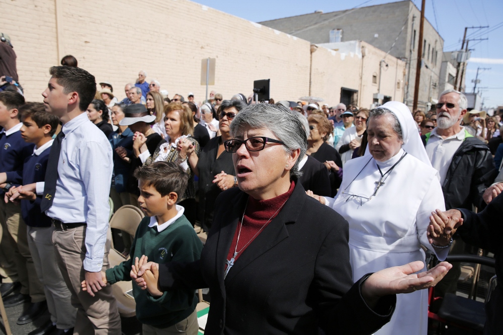 Minim Sr. Barbara Monsegur, high school principal at Lourdes Catholic School in Nogales, Ariz., joins hands with students during a Mass celebrated at the border April 1 in Nogales. (Nancy Wiechec)