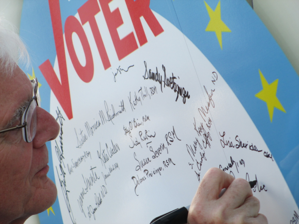 Another person pledges to be a voter by signing the Nuns on the Bus in Council Bluffs, Iowa. (Jan Cebula)