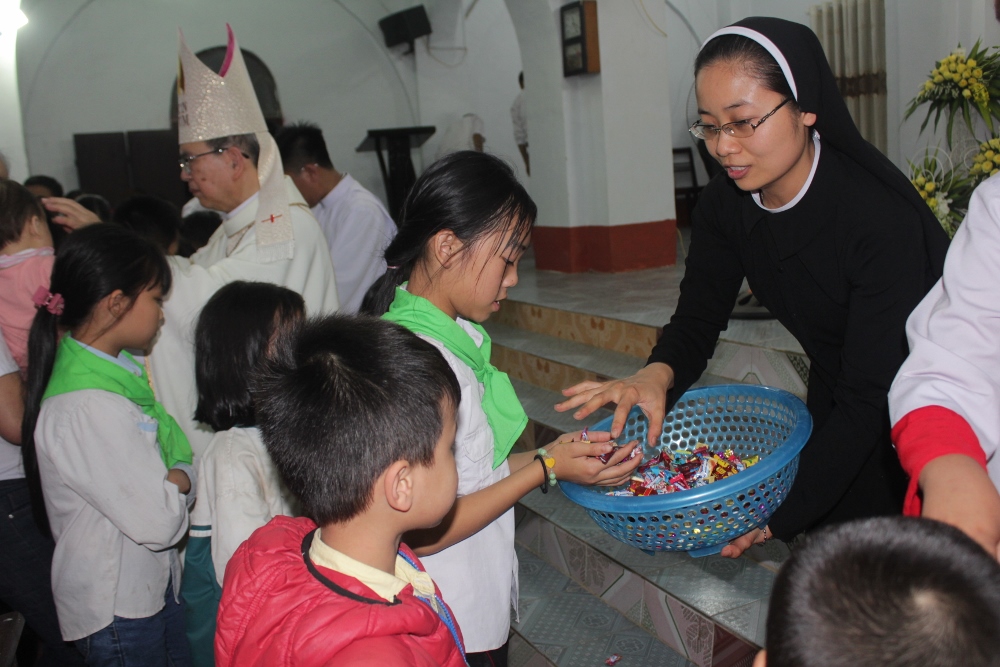 Sr. Maria Nguyen Thi Vinh hands out rosaries and sweets to people after the Easter Vigil Mass at Vinh Quang Church. (Joachim Pham)