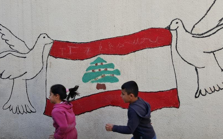 Passing children and the flag of Lebanon held aloft by doves on a street mural in Beirut hold out the hope for peace in a country that has known war. (GSR/Chris Herlinger)