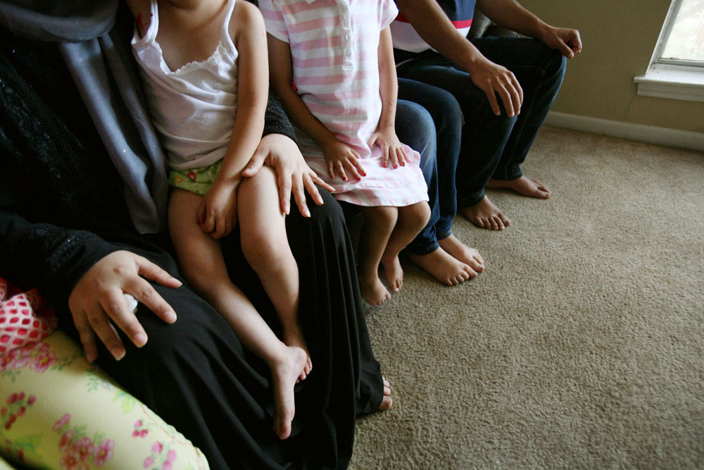 "Sham," left, and "Tariq," right, and their family from Syria sit in their new apartment in Houston after being resettled from Jordan in September. The family is being helped by staff from the Refugee Resettlement Program of Catholic Charities. (GSR photo / Nuri Vallbona)