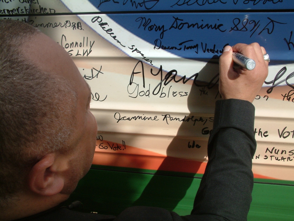 A man signs the bus parked outside of St. Luke's N.E.W. Life Center in Flint Township, Michigan. (Courtesy of NETWORK)