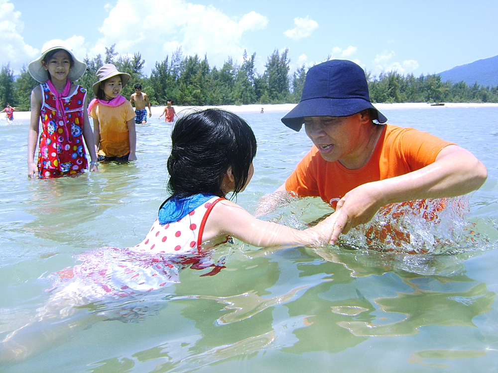 Sr. Teresa Nguyen Thi Lan (right) teaches a young girl how to swim in a river. (Peter Nguyen)