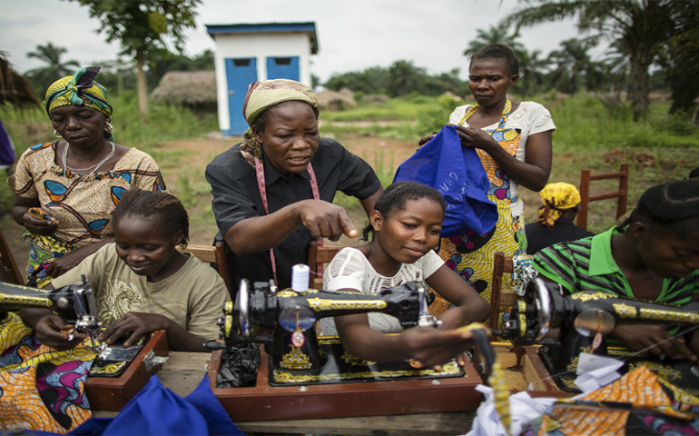 Sister Angélique Namaika, standing, in black, assists women with the clothes they are making at the Maison de La Femme in the town of Dungu, Orientale Province, Democratic Republic of Congo, on Aug. 1, 2013. (UN Refugee Agency/Brian Sokol)