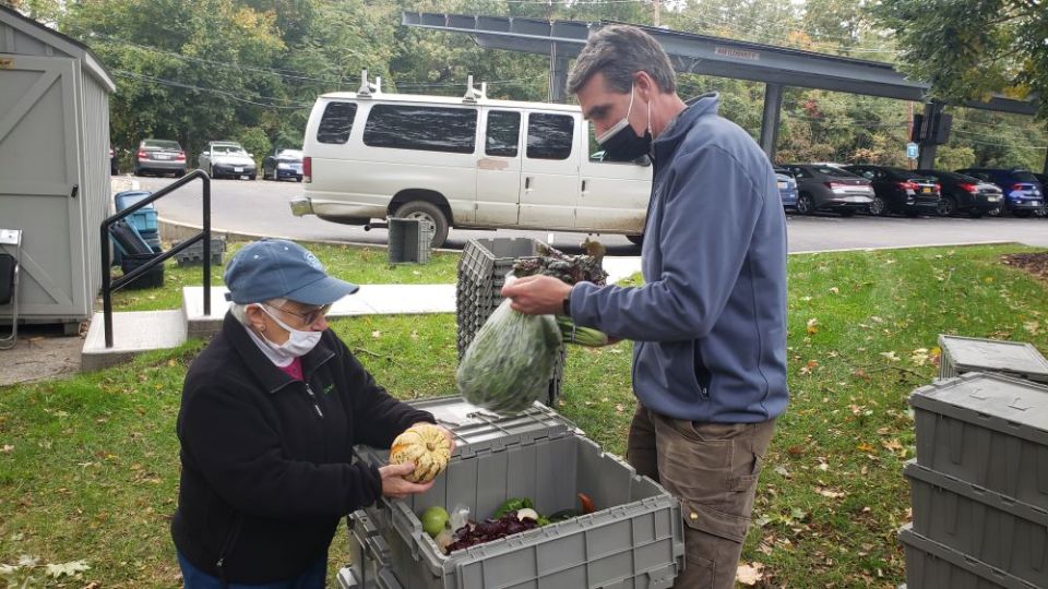 Sisters Hill Farm Director David Hambleton, right, and Farm Director Emeritus Sr. Mary Ann Garisto prepare a member's produce share to be picked up at the distribution at the College of Mount Vincent. (Chris Herlinger)