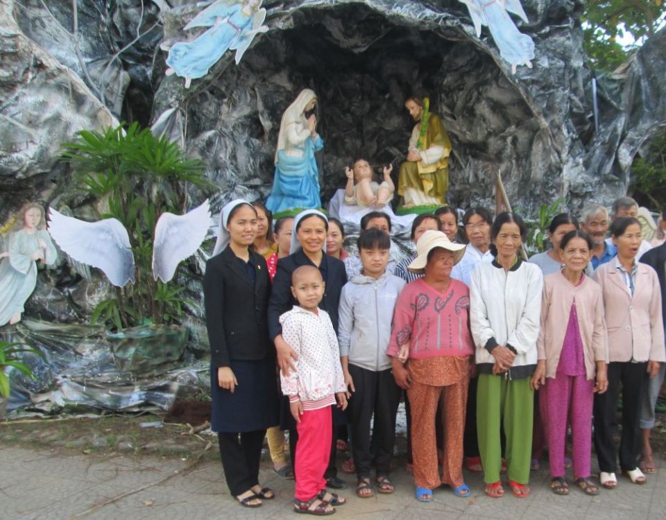Sr. Anna Vo Thi Ngoi Khen (second from left) and followers of other faiths stand in front of a big crèche on Dec. 12 at her convent in Thua Thien Hue province. (Joachim Pham)