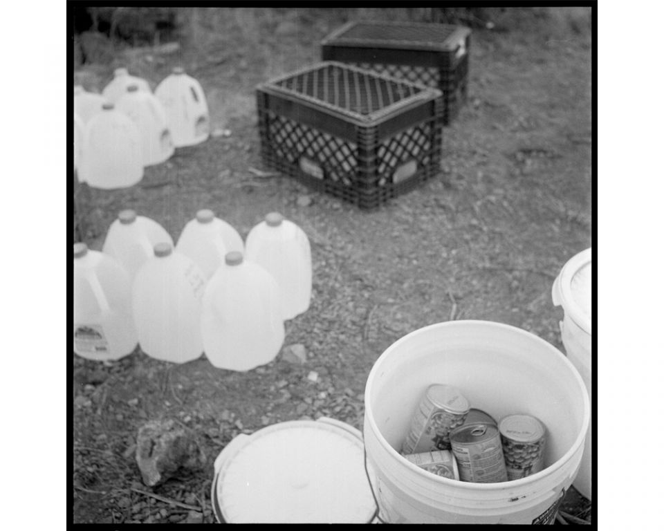 Water bottles are lined up and food is placed in buckets. Jugs are placed under milk crates to prevent animal damage to the bottles. In deciding how much to leave and where, the Samaritans base decisions on the data they record from the migrants' use of w