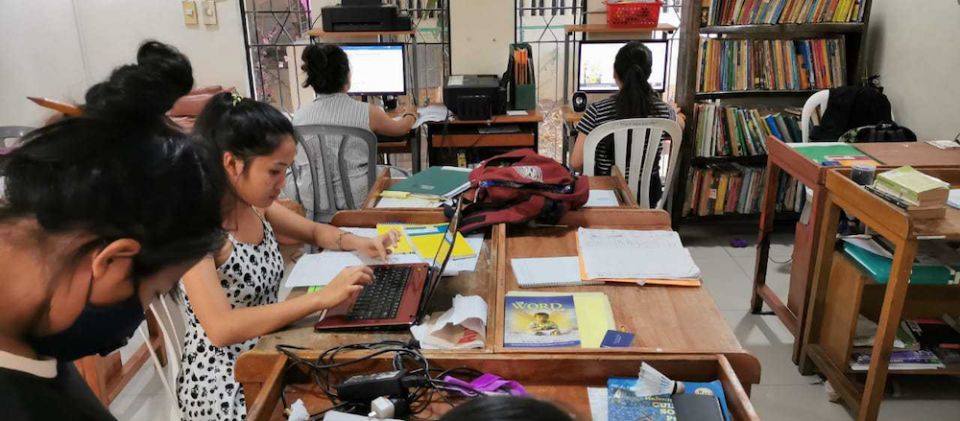 Because of the pandemic, Girls at the School of Life have been taking classes online with computers from donors and help from volunteer tutors. (Courtesy of the Missionaries of Mary) Various girls sit at tables and with computers and tablets working on school