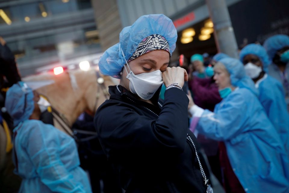 A nurse in New York City wipes away tears as police cheer and thank health care workers April 16 amid the coronavirus pandemic. (CNS/Reuters/Mike Segar)