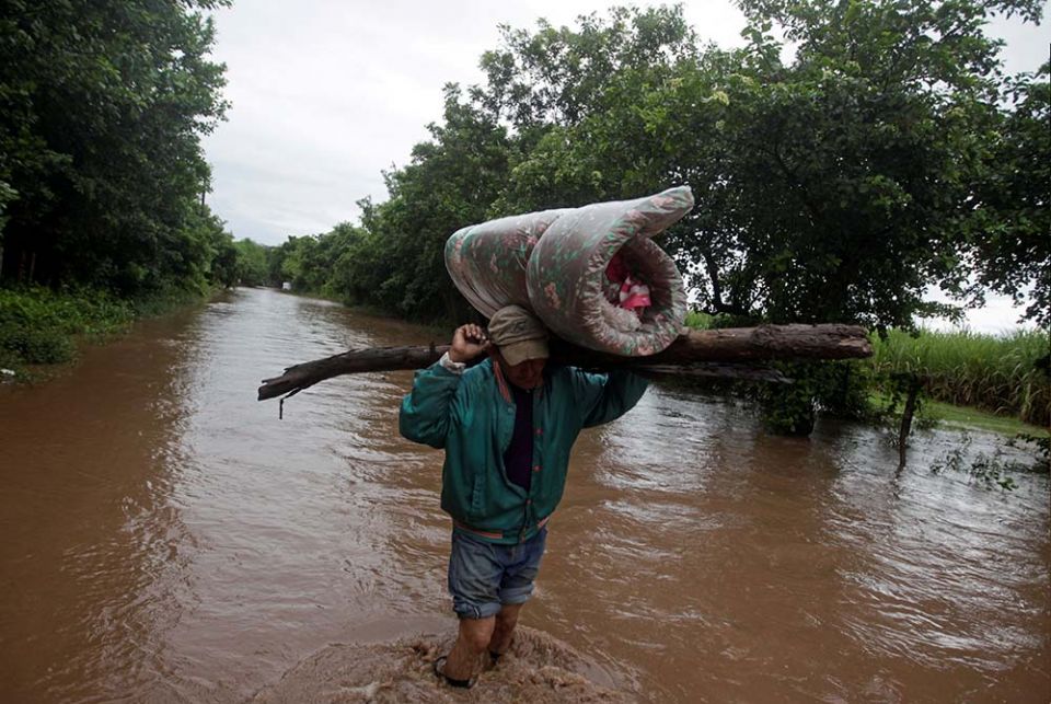 A man carries his belongings through a flooded road Nov. 18 in Marcovia, Honduras, after the passing of Hurricane Iota. (CNS/Jorge Cabrera, Reuters)