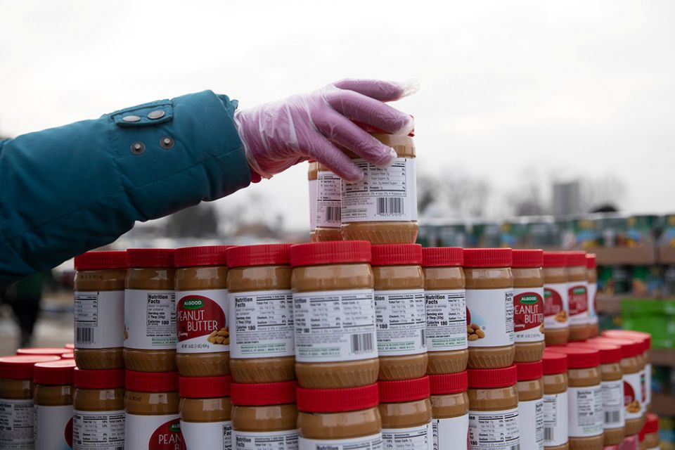 A volunteer from Forgotten Harvest food bank in Warren, Michigan, sorts jars of peanut butter during a mobile food pantry distribution Dec. 21, 2020. (CNS/Reuters/Emily Elconin)