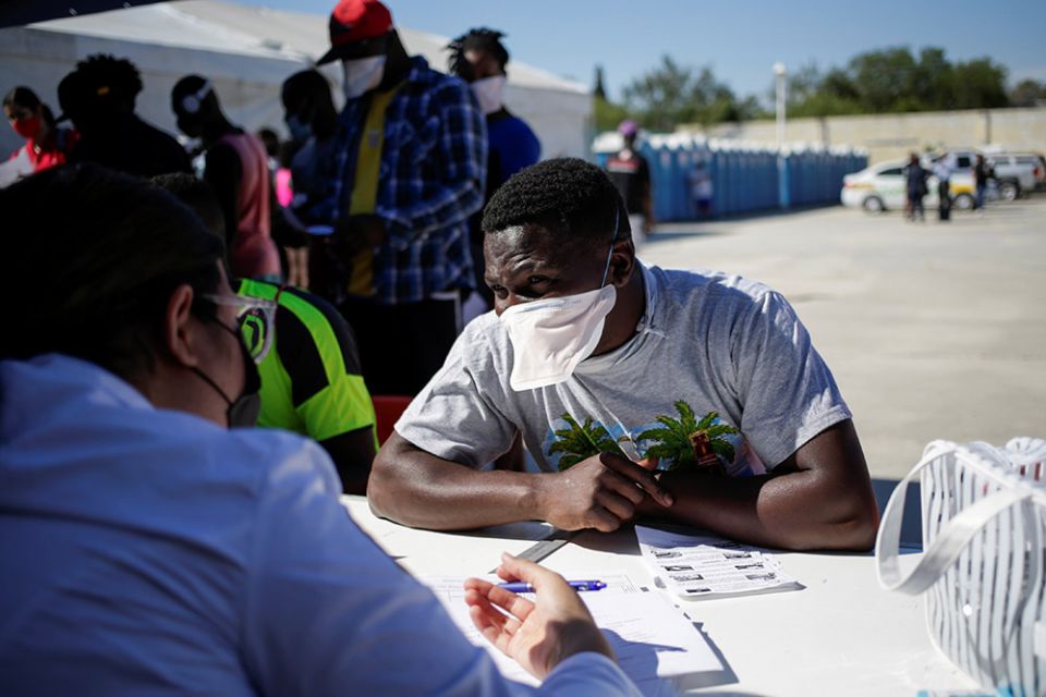 A migrant from Haiti, who returned to the Mexican side of the border to avoid deportation, listens to a health care worker at a shelter set by the National Migration Institute in Ciudad Acuña, Mexico, Sept. 25. (CNS/Reuters/Daniel Becerril)
