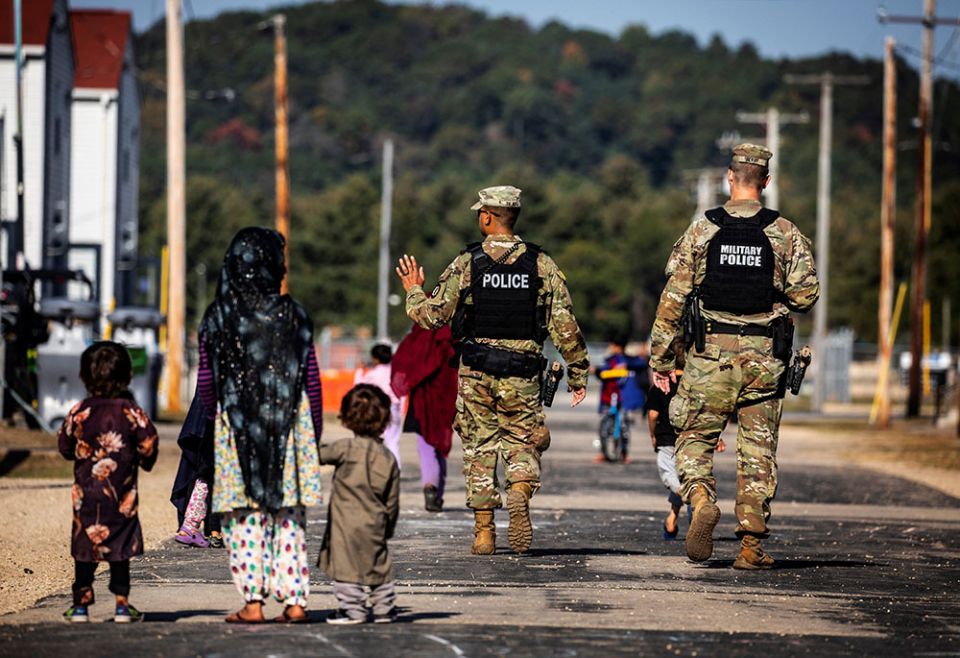 U.S. Military Police walk past Afghan refugees at Fort McCoy U.S. Army base in Wisconsin Sept. 30. (CNS/Barbara Davidson, Pool via Reuters)