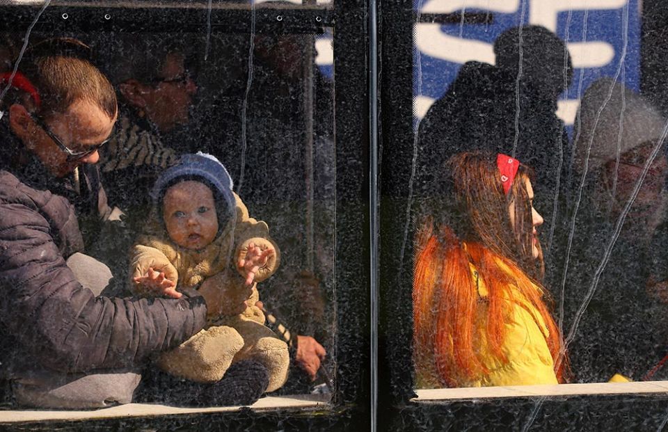 A baby looks out of a bus going to Poland, as people flee the ongoing Russian invasion, outside the main train station in Lviv, Ukraine, March 14. (CNS/Reuters/Kai Pfaffenbach)