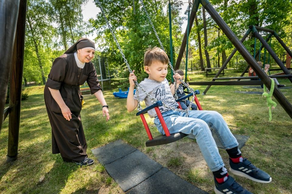 Sister Alicja of the Franciscan Sisters Servants of the Cross pushes Ukrainian refugee Jan, 6, at the monastery where they help blind children in Laski, Poland, on May 20. (CNS/Lisa Johnston)