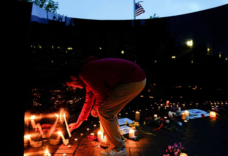 A person in the Chicago suburb of Highland Park, Illinois, lights a candle at a memorial site July 5 near the parade route the day after a mass shooting at a Fourth of July parade. Seven people were killed and dozens injured. (CNS/Reuters/Cheney Orr) A person in the Chicago suburb of Highland Park, Illinois, lights a candle at a memorial site July 5 near the parade route the day after a mass shooting at a Fourth of July parade. Seven people were killed and dozens injured. (CNS/Reuters/Cheney Orr)